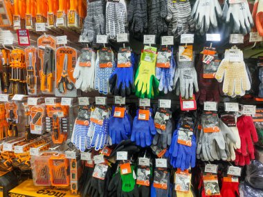 Endonezya-Balikpapan-Endonezya 15 Mart 2026 Çeşitli endüstriyel iş eldivenleri ve profesyonel el aletleri bir mağaza rafında asılı. Perakende deposunda ya da atölyede düzgün bir koruyucu teçhizat ve donanım düzenlemesi.