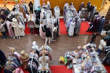 Balikpapan-Endonezya 15 Mart 2026 Alışverişçiler kalabalık bir perakende pazarında renkli Müslüman modası ve geleneksel kıyafetlerden oluşan geniş bir yelpazeye bakıyorlar. Mevsimlik bir satış sırasında bir giysi sergisinin yüksek açılı görüntüsü.