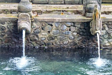Pura Tirta Empul, Bali, Endonezya 'da iki kutsal taş çeşmesi. Ön açı, dingin bir ruh hali ve mükemmel bir odaklanma ile akan kutsal suyu yakalar. Maneviyat, kültür ve seyahat konsepti için ideal..