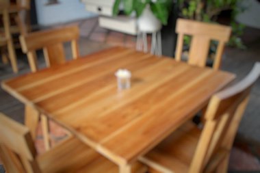 Yumuşak odaklı ahşap masa ve Kuta Beach Bali yakınlarındaki sıcak bir kafede sandalyeler. Bulanık arka planlı, göz hizasında doğal bir ortam. Kafe, yaşam tarzı, konukseverlik, yemek temaları için mükemmel..