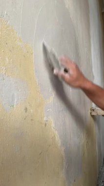 Bir inşaat işçisinin duvar bileşimini boyamadan önce macun bıçağıyla uyguladığı 4K 'lık yakın çekim. Keskin odak ile kenar açı atışı. Sakin, çalışkan bir ruh hali. Yenileme ve inşa için ideal, vs..