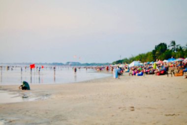 Kuta Beach, Bali, Endonezya 'daki bulanık plaj sahnesi, göz hizasında çekilmiş. Yumuşak odaklı kalabalık ve kıyı şeridi sakin bir tatil havası yaratıyor, seyahat, turizm, yaz yaşam tarzı ve soyut arka plan tasarımları için ideal.