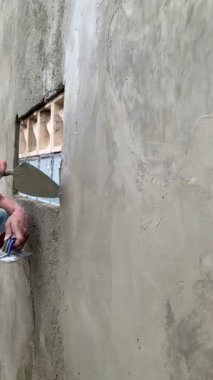 İnşaat işçisinin 4 km 'lik görüntüsü beton alçıyı duvara yapıştırıyor. Dikey açı sabit eller, odaklanma ve adanmışlık gösteriyor. İnşaat, yenileme, işçilik, inşaat süreci kavramları için ideal.