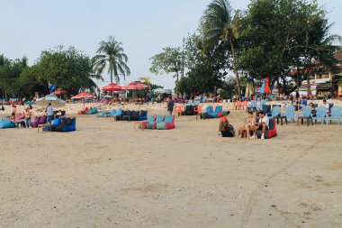 Kuta Beach Bali 'nin geniş kıyı sahnesinde insanlar deniz kenarında yürüyor ve dinleniyor. Doğal ışık ve açık alan, seyahat, turizm ve yaşam tarzı temaları için uygun sakin, sosyal bir atmosfer yaratır. 11 Eylül 2024 - Endonezya.