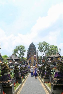 Turistler, Bali 'nin Ubud kentindeki süslü Saraswati Tapınağı' nın nilüfer havuzları ve taş heykellerle çevrili yolu boyunca yürüyorlar. Karmaşık Balili mimari ve canlı atmosfer kültürel ve seyahat temaları için mükemmeldir. 11 Eylül 2024