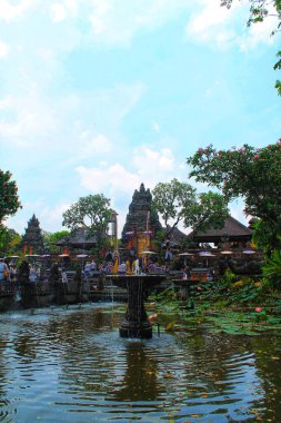 Ubud, Bali 'deki Saraswati Tapınağı' nın (Pura Taman Saraswati) geniş açılı manzarası. Süslü tapınak kapısı ve turistlere giden nilüferlerle dolu yemyeşil bir nilüfer havuzunda taştan bir çeşme bulunuyor. 11 Eylül 2024-Endonezya.