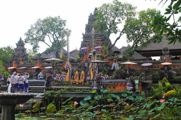 Ubud, Bali 'deki Saraswati Tapınağı' nın (Pura Taman Saraswati) geniş açılı manzarası. Süslü tapınak kapısı ve turistlere giden nilüferlerle dolu yemyeşil bir nilüfer havuzunda taştan bir çeşme bulunuyor. 11 Eylül 2024-Endonezya.