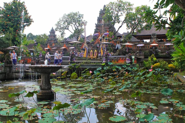 Ubud, Bali 'deki Saraswati Tapınağı' nın (Pura Taman Saraswati) geniş açılı manzarası. Süslü tapınak kapısı ve turistlere giden nilüferlerle dolu yemyeşil bir nilüfer havuzunda taştan bir çeşme bulunuyor. 11 Eylül 2024-Endonezya.