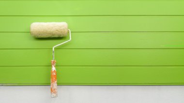 Duvar yeşil arka plan üzerinde izole yeni boya silindiri.