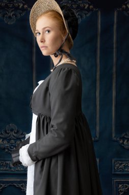 Beyaz çarşaf giyen bir naip kadın ve Spencer bir odada dikiliyorlar.