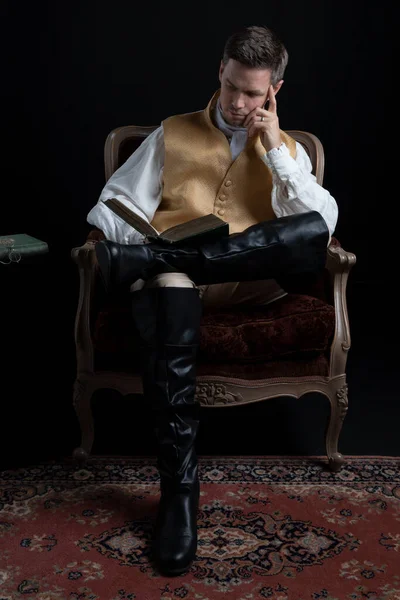 Przystojny Regencyjny Mężczyzna Złotej Kamizelce Bryczesach Siedzący Czerwonym Aksamitnym Fotelu — Zdjęcie stockowe