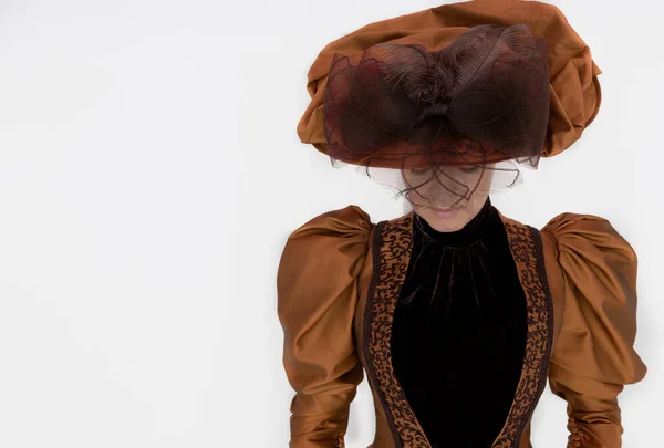 一个维多利亚时代的女人 身穿青铜和褐色丝绸服装 头戴大帽子 在白色的背景前摆姿势 — 图库照片