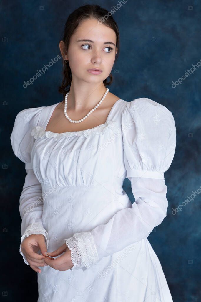A young Regency woman standing alone against a blue backdrop