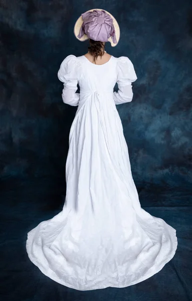 白いムスリンのドレスを着た若いリージェンシー女性とバックビューに表示される藁ボンネット — ストック写真