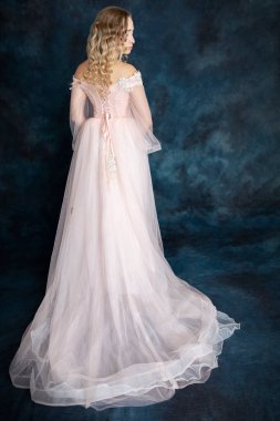 Pembe prenses elbisesi giymiş, uzun trenli güzel bir sarışın kadın.