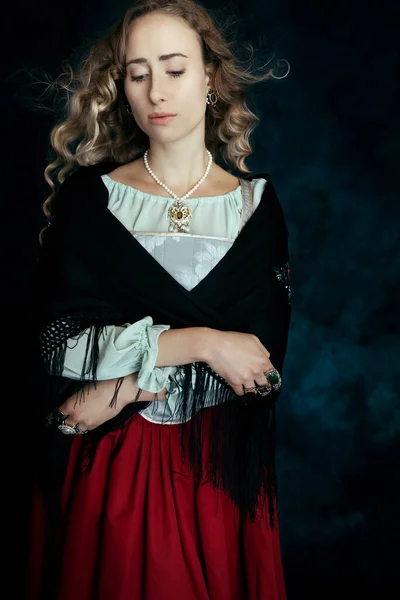 A Renaissance woman in a brocade corset and red skirt