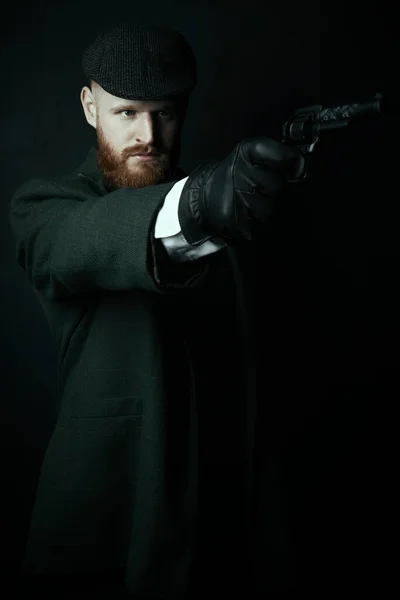 Victorian man wearing a tweed suit and flat cap holding a gun