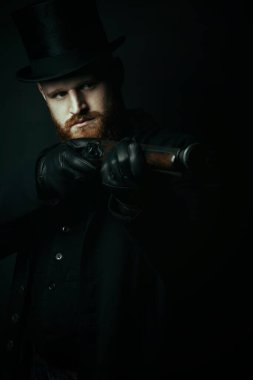 Viktorya Dönemi 'nden tüvit takım elbiseli ve elinde silah tutan bir adam.