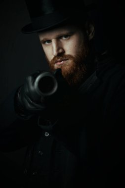 Viktorya Dönemi 'nden tüvit takım elbiseli ve elinde silah tutan bir adam.