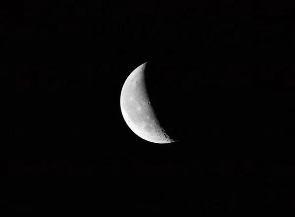 The quarter moon in the dark of the night sky.