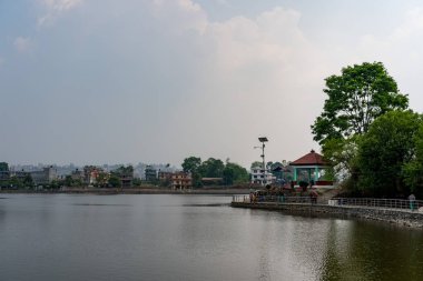 Parkta bir göl, arka planda bir şehir..