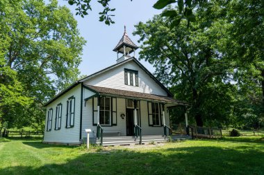 Meşe ve akçaağaç ağaçlarının altında eski bir okul..