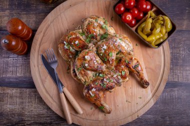 Tahta tahtada kiraz domatesli, biberli, sarımsaklı ve kişniş soslu Tapaca (tabaca) tavukları. Geleneksel Gürcü yemeği. Yakın plan..