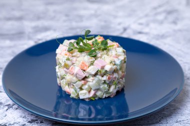 Mavi tabakta bezelye filizleriyle süslenmiş Olivier salatası. Geleneksel Yeni Yıl ve Noel Rus salatası. Yakın çekim, seçici odaklanma.