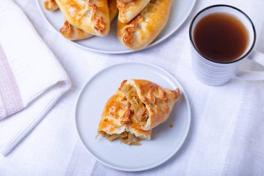 Lahanalı turtalar (pirozhki). Ev yapımı pişirme. Geleneksel Rus ve Ukrayna mutfağı. Arka planda turtalarla dolu bir tabak var. Yakın plan..