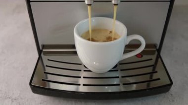 Kahve makinesinden beyaz fincana kahve dökme işlemi. Kahvaltı için taze sıcak espresso. Yavaş çekim, yakın çekim..