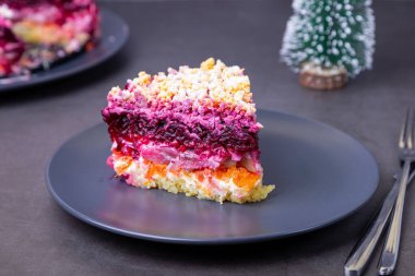 Kürk mantonun altında ringa salatası. Ringa, pancar, patates, havuç ve yumurtadan geleneksel Rus çoklu salatası. Küçük Noel ağacı. Yakın plan, gri arkaplan.