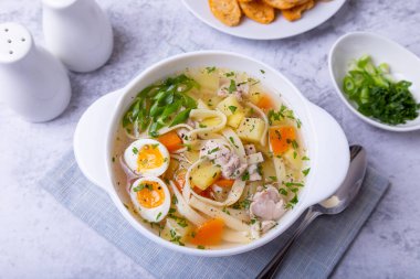 Tavuk, erişte, patates, bıldırcın yumurtası ve havuçlu çorba. Soğan ve maydanozla tatlandırılmış. Yakın plan..