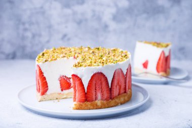 Taze çilek ve şam fıstıklı Freesier keki. Klasik Fransız tatlısı. Beyaz bir tabakta yakın plan kek..