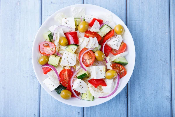 ギリシャのサラダ 伝統的なギリシャ料理 健康的なベジタリアン料理 白皿に新鮮な野菜やフェタチーズ クローズアップ 青の背景 — ストック写真