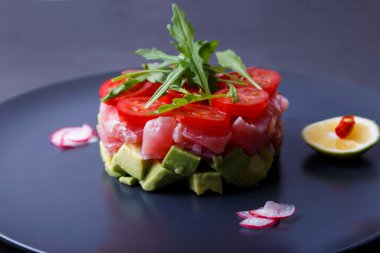 Avokado, roka, vişneli domates, turp, acı biber ve limonlu taze ton balığı. Fransız mutfağının geleneksel soğuk aperatifi. Yakın çekim, seçici odaklanma.