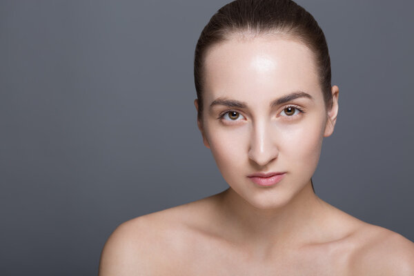 Beauty fashion vogue style face of caucasian brunette with elegant make-up, blue eyes, natural lips touching perfect skin. Close-up studio portrait isolated. Black background with grey spot.