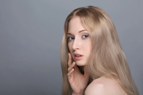 Vertrauen in ihre Fähigkeiten. lächelnde junge Frau mit blonden Haaren, die die Hände auf den Hüften hält und vor grauem Hintergrund in die Kamera blickt — Stockfoto