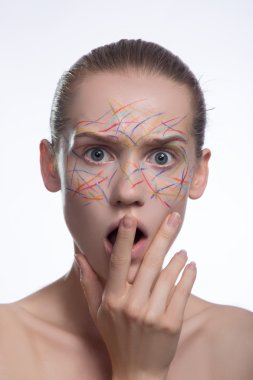 Bir kadında geometrik makyaj ile yaratıcı güzellik. Beyaz çizgiler ve güzel bir genç kusursuz yüz gri kil lekeler. nötr arka plan. duygusal portre