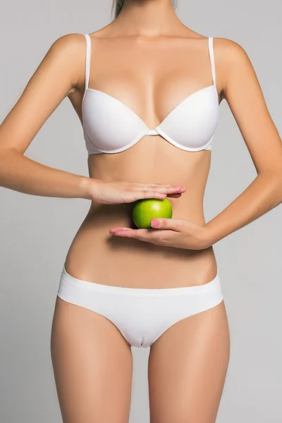 Photo de femme tenant pomme verte devant son ventre en lingerie blanche ou sous-vêtements mode et beauté spa massage — Photo