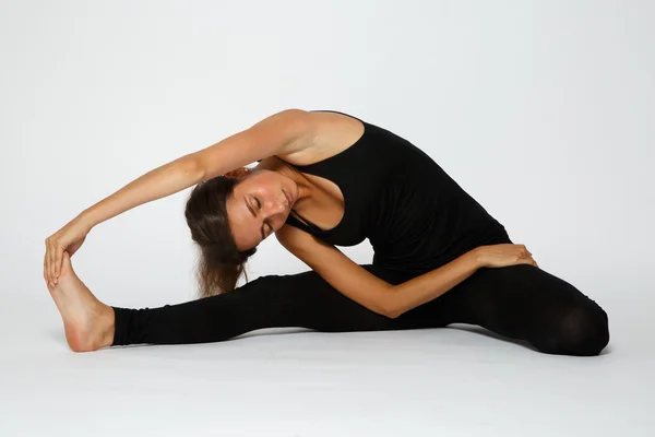 Girl makes yoga exercise on the white background in black — Stock Photo, Image