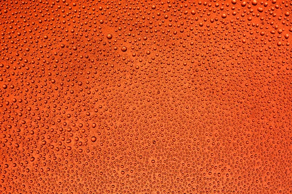 Gotas de água no vidro com um fundo vermelho — Fotografia de Stock