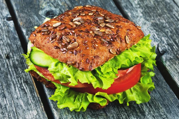 Sandwich mit Getreidebrot, mit Schinken und Gemüse, grünem Salat auf Holzgrund — Stockfoto
