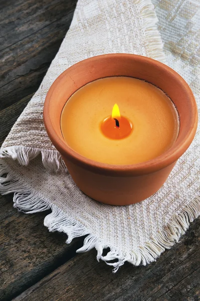Горящая свеча в глиняном горшке на деревянном фоне — стоковое фото