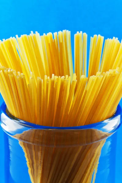 Uncooked pasta spaghetti macaroni on blue background — Stock Photo, Image