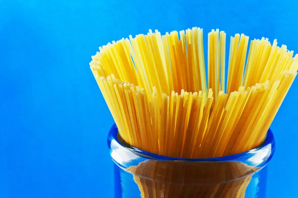 Macarrones de espagueti de pasta sin cocer sobre fondo azul —  Fotos de Stock