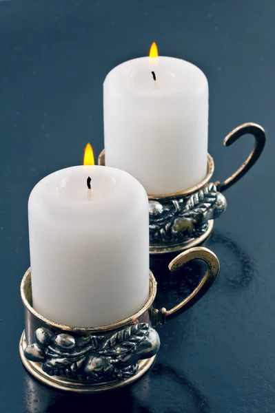 Dos velas blancas ardientes en un candelero sobre un fondo azul —  Fotos de Stock