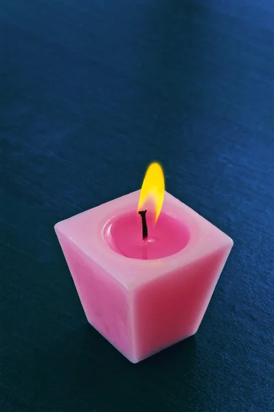 Одна горящая белая свеча на синем фоне — стоковое фото