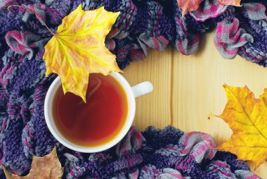 Bir fincan çay, eşarp ve akçaağaç yaprakları