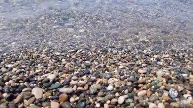 Çakıl taşları üzerinde açık deniz dalgaları. Yan görünüm.