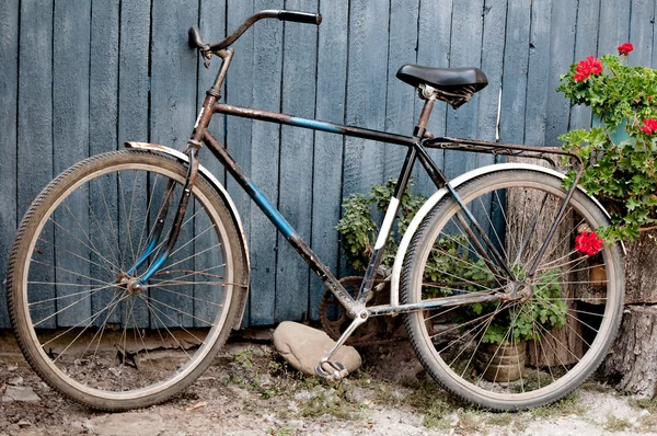 Old  bicycle near a blue wooden fence in village — Stock Photo, Image